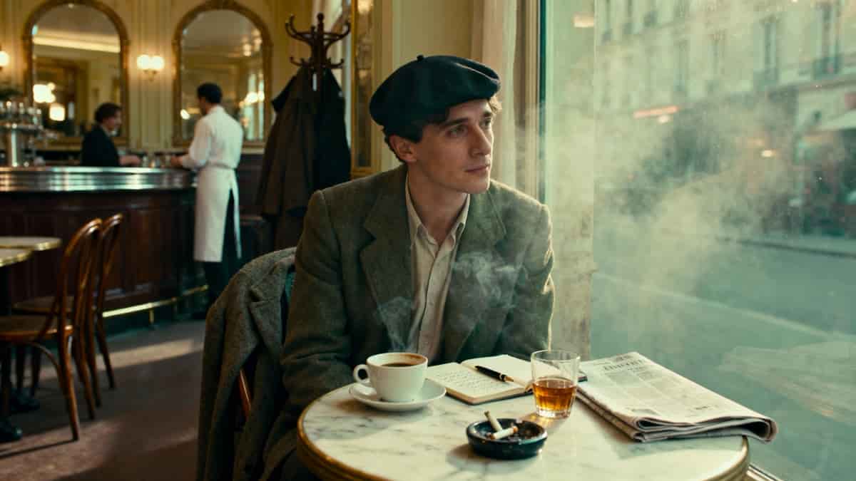 Écrivain attablé dans un café parisien avec sa tasse de café vide et son petit verre de liqueur en pousse-café.
